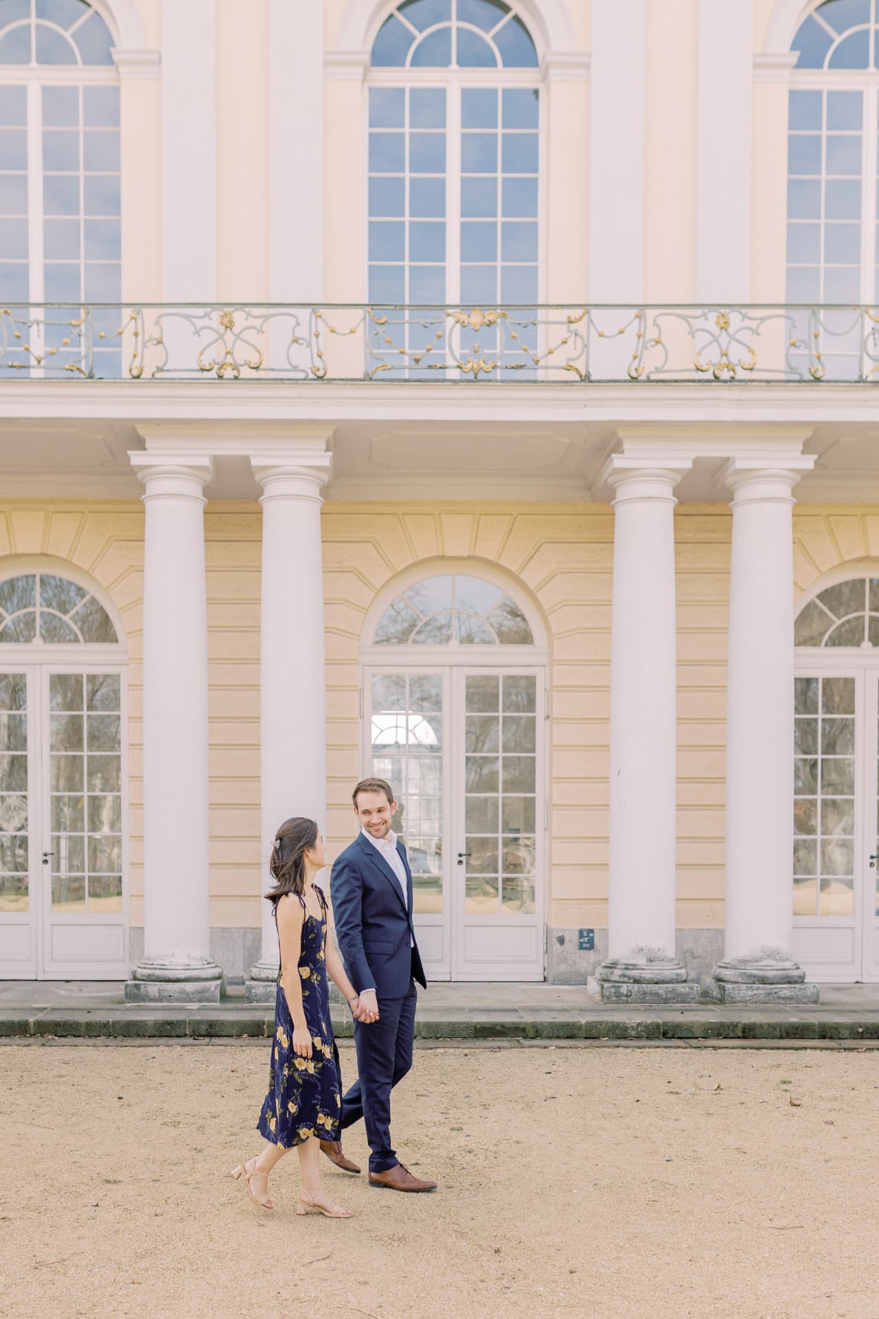 Laura und Peter gehen Hand in Hand am Schloss entlang